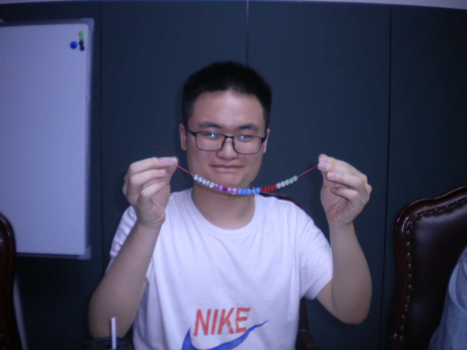 穿白色印花 T 恤的同学展示串起的彩色珠子