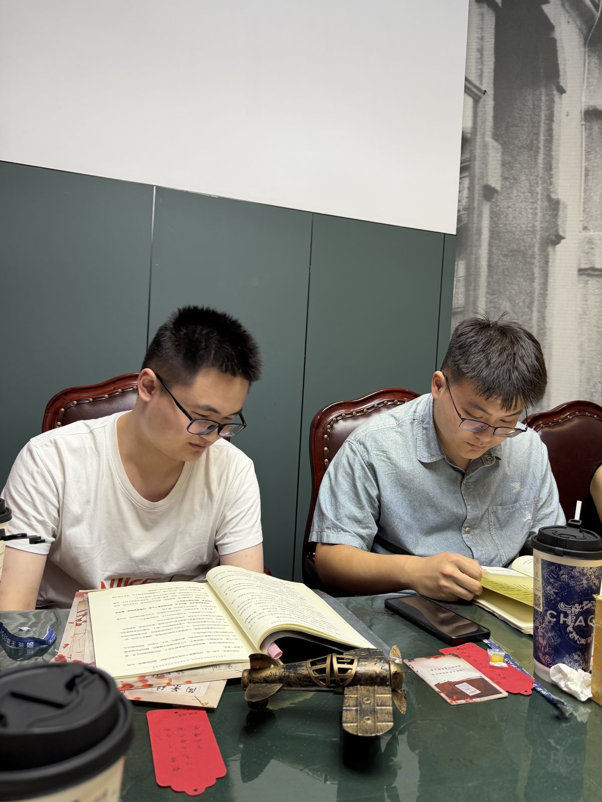 两位同学低头阅读剧本,桌上摆着小飞机模型